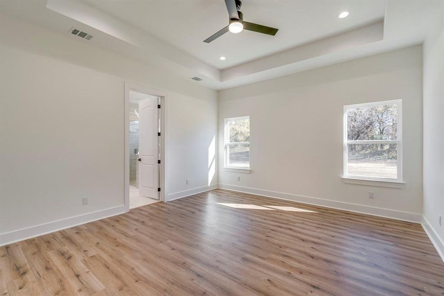 Empty room featuring light hardwood / wood-style floors, a raised ceiling, and ceiling fan