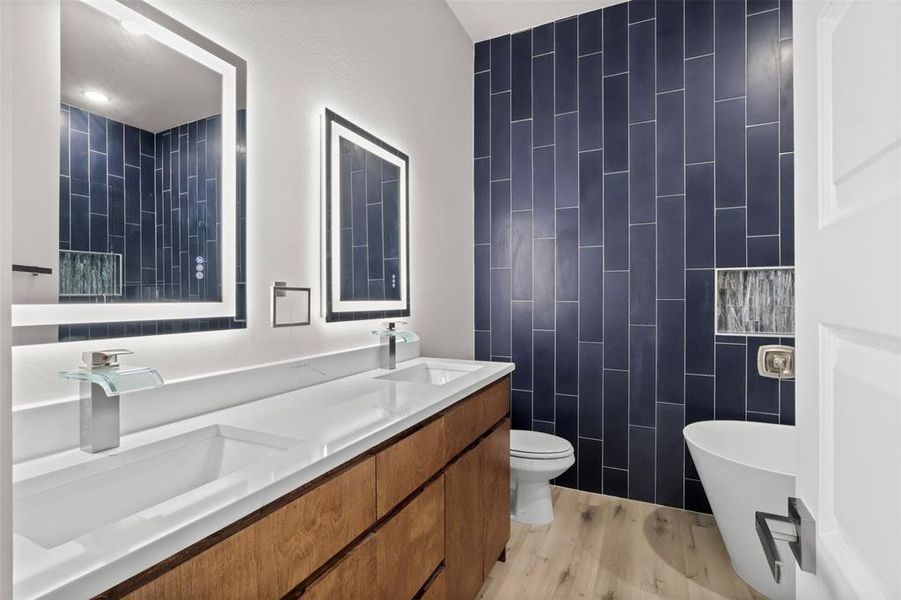 Bathroom with wood-type flooring, toilet, a bathtub, vanity, and tile walls