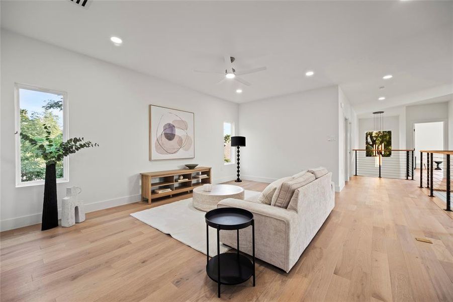 Living room with ceiling fan and light hardwood / wood-style floors