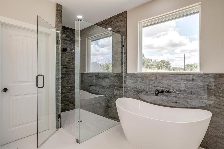 Bathroom featuring tile walls and separate shower and free standing tub