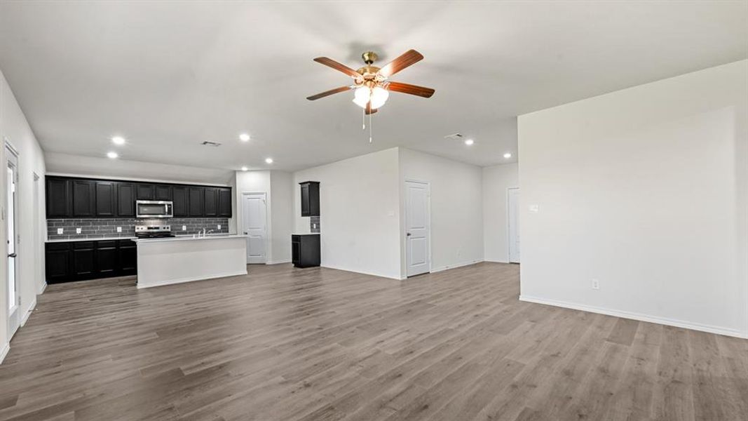 Expansive open-concept living area featuring wood-finish flooring, recessed lighting, and a ceiling fan