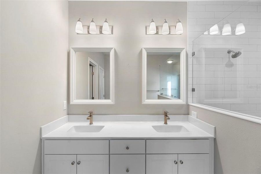 The double-sink vanities feature custom cabinetry and brushed nickel faucets, enhancing the elegance of the spacious primary bath suite.