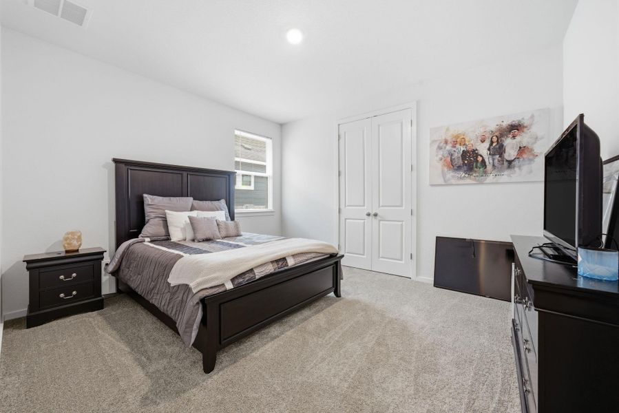 Bedroom with light carpet, a closet, and an office area