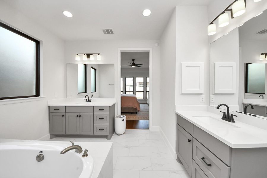 Well-designed primary bath with separate vanities and private access.