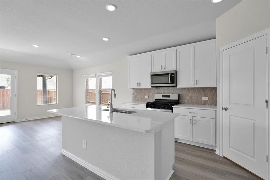 Kitchen featuring recessed lighting, gas range, white cabinetry, decorative backsplash, and stainless steel microwave Kitchen featuring recessed lighting, gas range, white cabinetry, decorative backsplash, and stainless steel microwave