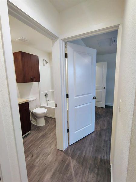 Bathroom with hardwood / wood-style floors, toilet, and tub / shower combination