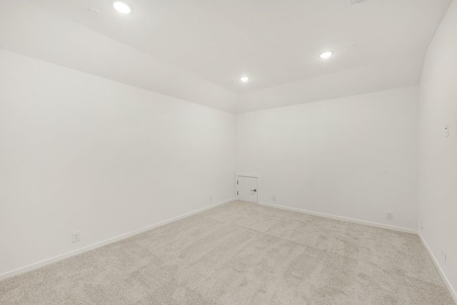 Empty room with white walls, beige carpet, recessed lighting, and a single door