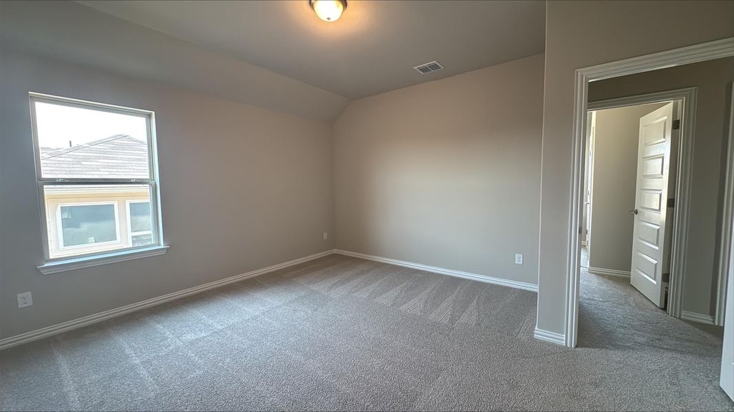 Unfurnished room featuring light carpet and vaulted ceiling