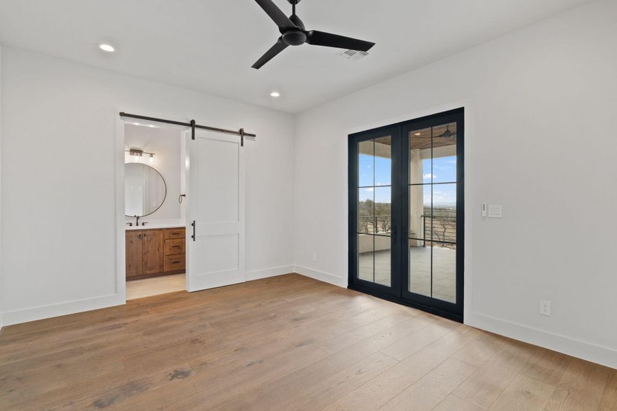 2 of 3 bedroom upstairs with barn door to bathroom and french doors out to balcony with hill country views.