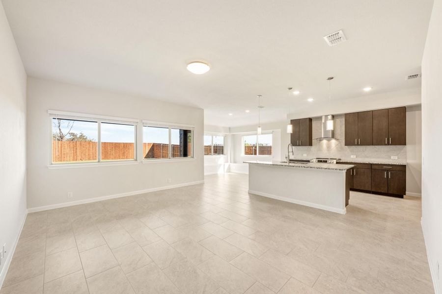 Open-concept living area and kitchen with dark cabinets, center island, and tile floors
