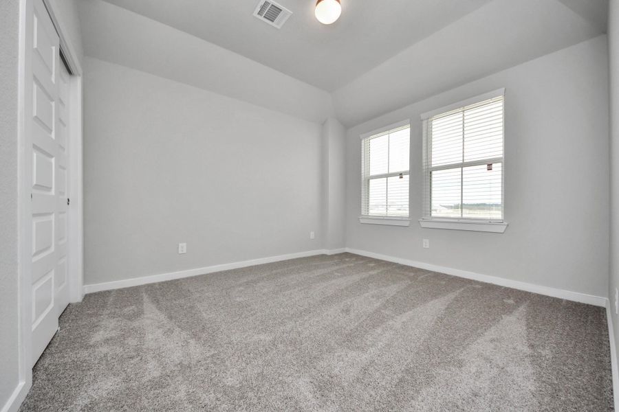 Secondary bedroom features plush carpeting, large windows that let in plenty of natural light, bright paint, and spacious closets. Sample photo of completed home with similar floor plan. Actual colors and selections may vary.