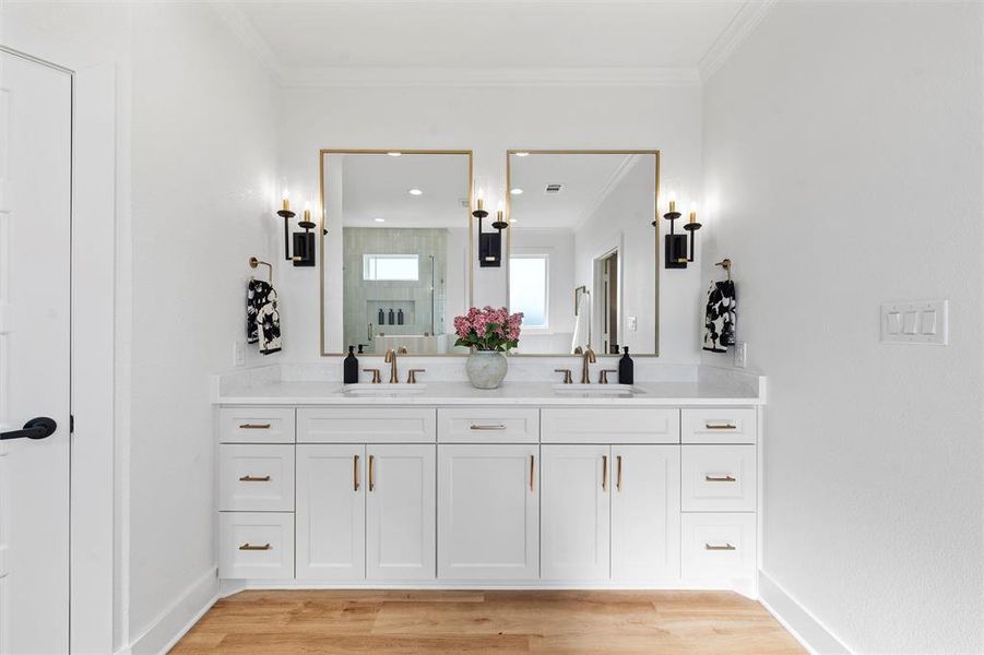 Bathroom with double vanity, crown molding, a stall shower, and wood finished floors