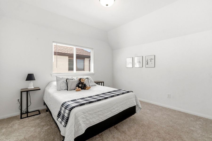 This photo showcases a bright, minimalist bedroom with neutral tones. The room has a cozy carpet and a window allowing natural light.