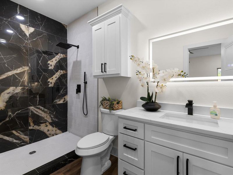 Bathroom with vanity, a marble finish shower, and dark wood finished floors