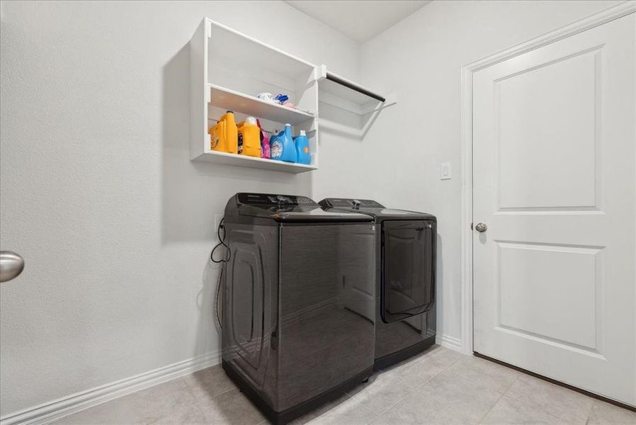 Clothes washing area featuring separate washer and dryer and light tile patterned floors