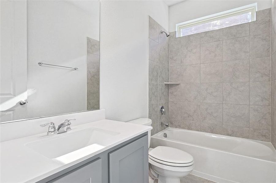 Full bathroom featuring vanity, tiled shower / bath combo, and toilet