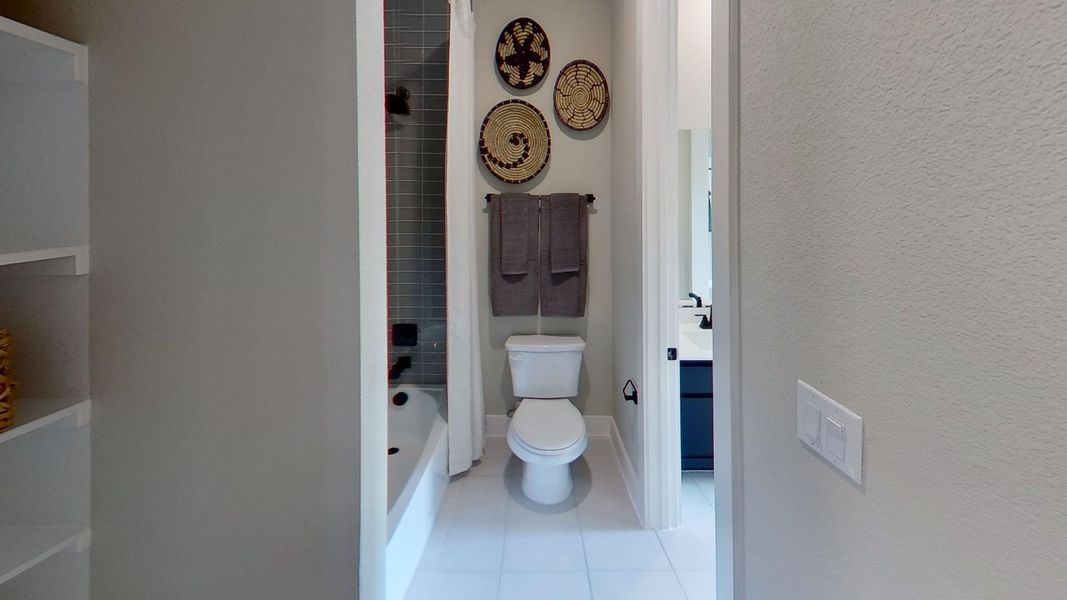 Bathroom with vanity, light tile patterned floors, a textured wall, and bathing tub / shower combination