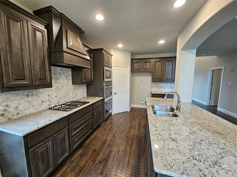 Kitchen features built-in stainless double ovens, gas cooktop, and a custom cabinet vent hood