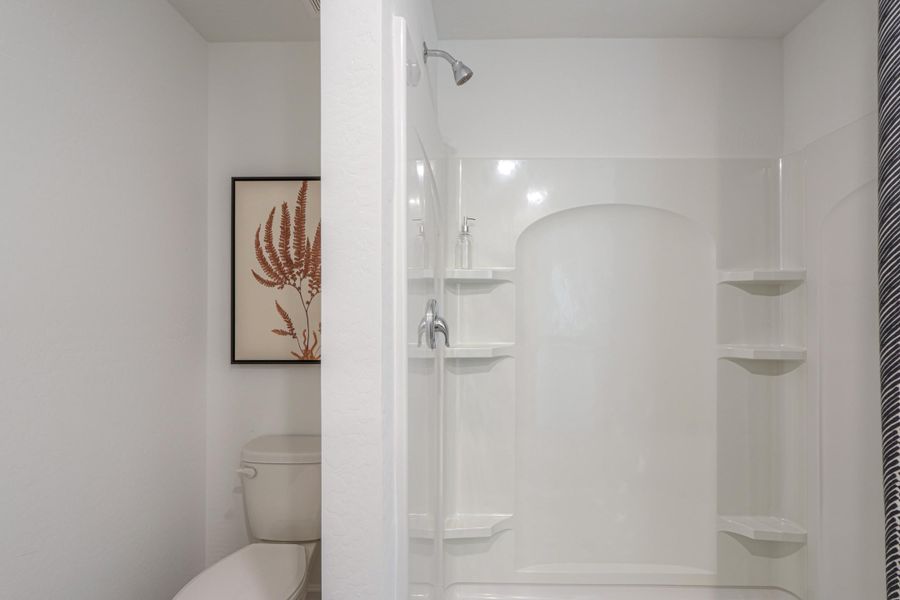 A bathroom with a shower unit and toilet.