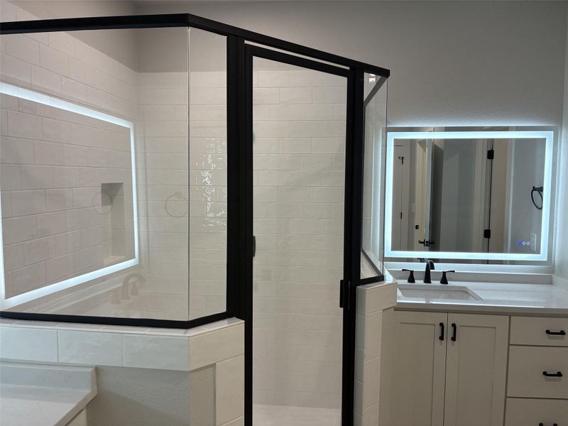 Modern bath with walk-in shower and illuminated vanity mirror provides a clean aesthetic. Modern bath with walk-in shower and illuminated vanity mirror provides a clean aesthetic.