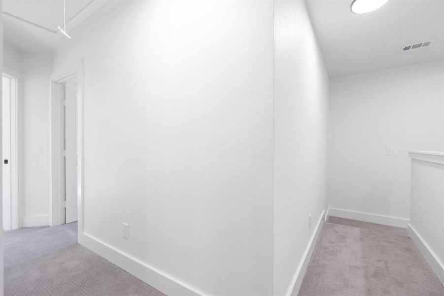 Hallway with light carpet and attic access