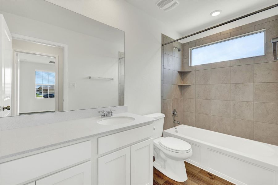 A well-appointed full guest bath features a spacious vanity and a bathtub with tile surround, offering both comfort and practicality.