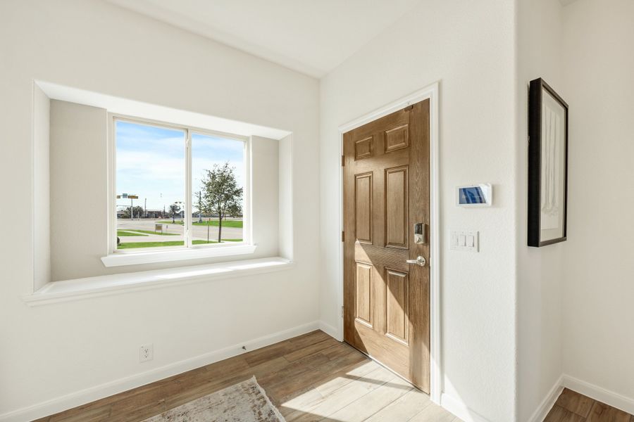 Entryway with wood panel door, hardwood floors, and large window with outdoor view