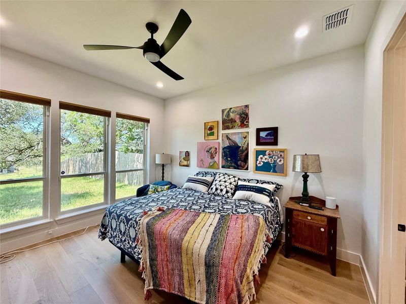 Spacious king size primary bedroom featuring light wood-finish flooring, recessed lighting, and a modern ceiling fan