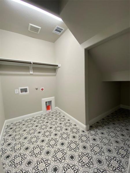 Utility room with extra storage under the stairs has custom decorative tile