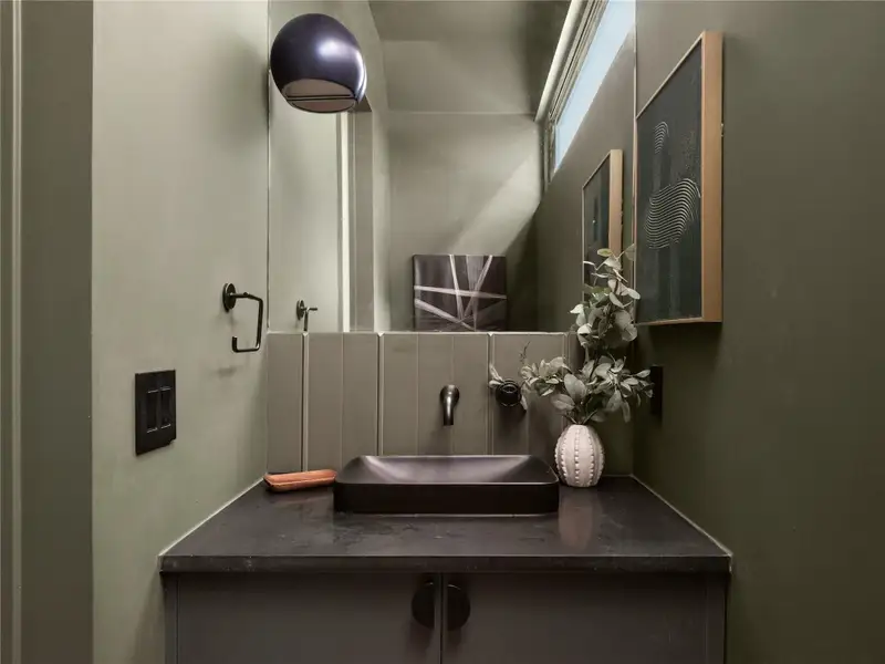 A sleek powder room features a modern vessel sink set against a textured tile backsplash. A sleek powder room features a modern vessel sink set against a textured tile backsplash.