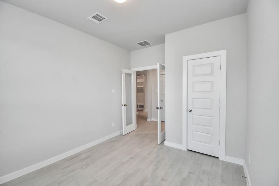 Experience the perfect blend of sophistication and warmth in this home office, boasting elegant wood-look tile flooring and flooded with natural light from expansive windows and French doors. Sample photo of completed home with similar floor plan. Actual colors and selections may vary.