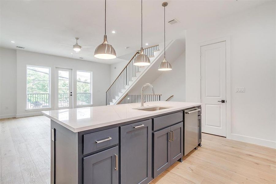 Kitchen featuring gray cabinets, dishwasher, light wood-style flooring, and a sink