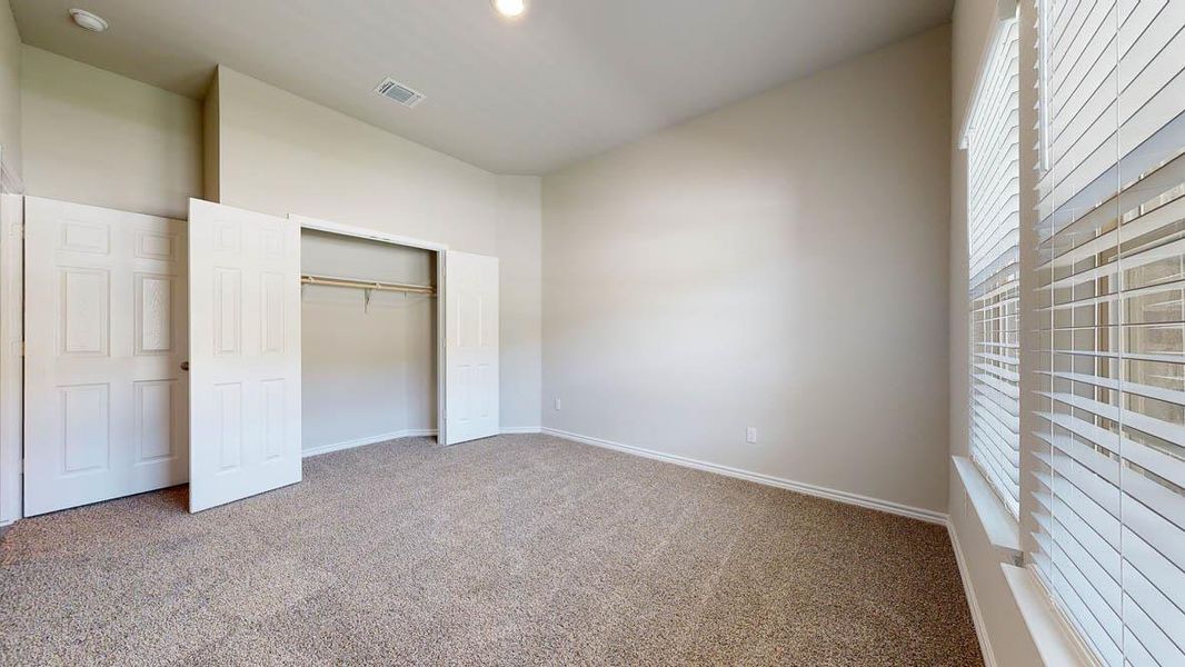 Carpeted room featuring a window with white blinds, a built-in closet with bifold doors and a clothes rod, and neutral wall paint