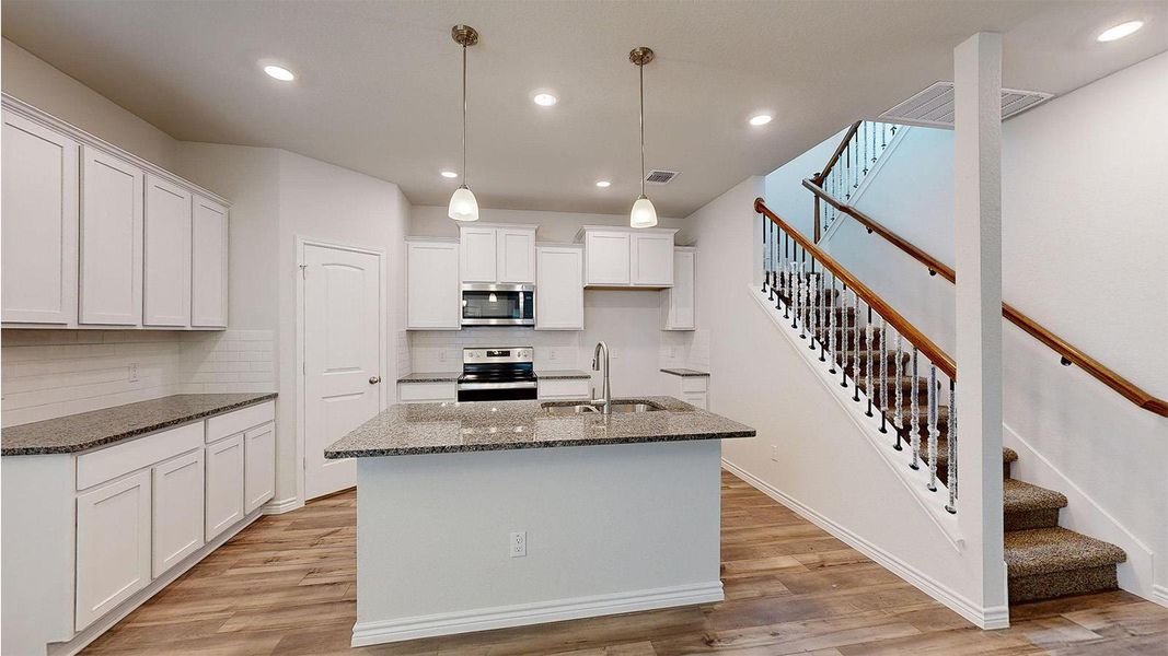 Kitchen featuring white cabinetry, granite countertops, subway tile backsplash, and stainless steel appliances Kitchen featuring white cabinetry, granite countertops, subway tile backsplash, and stainless steel appliances