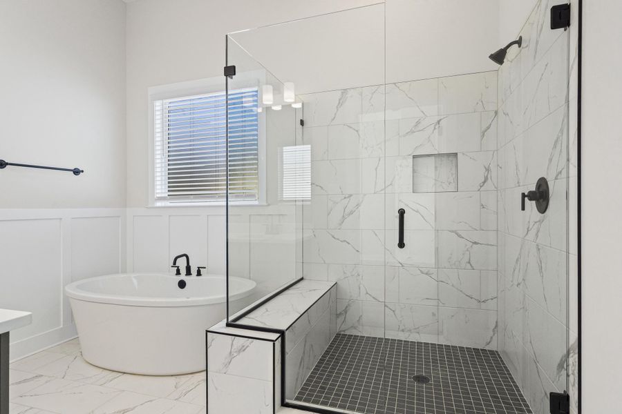 Bathroom with a marble finish shower, a freestanding bath, wainscoting, vanity, and marble look tiles Bathroom with a marble finish shower, a freestanding bath, wainscoting, vanity, and marble look tiles