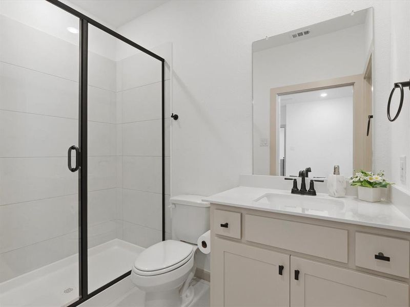 Bathroom featuring a glass-enclosed shower with black trim, a white vanity with an integrated sink, a large wall-mounted mirror, and black fixtures