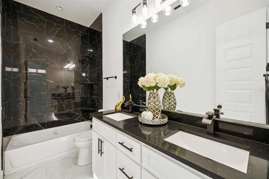 Bathroom featuring shower / washtub combination, double vanity, and light marble finish floors