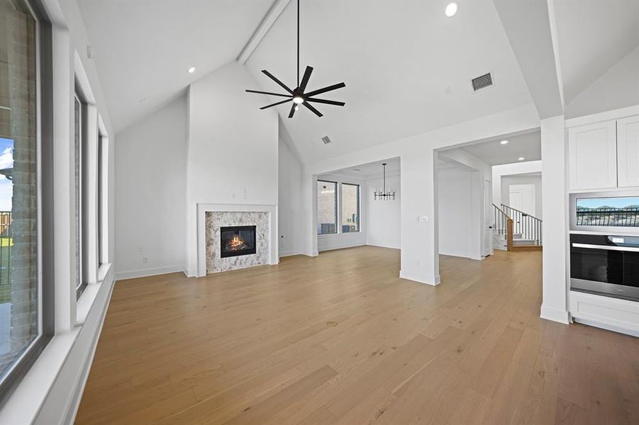 Unfurnished living room with beamed ceiling, ceiling fan, light wood-style floors, high vaulted ceiling, and recessed lighting
