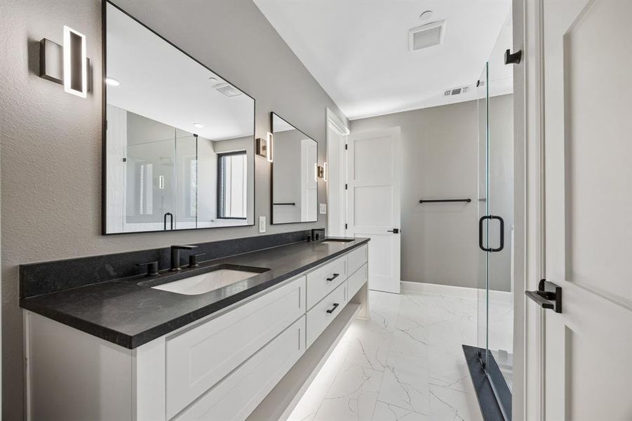 Bathroom with double vanity, light marble finish floors, and a shower stall Bathroom with double vanity, light marble finish floors, and a shower stall