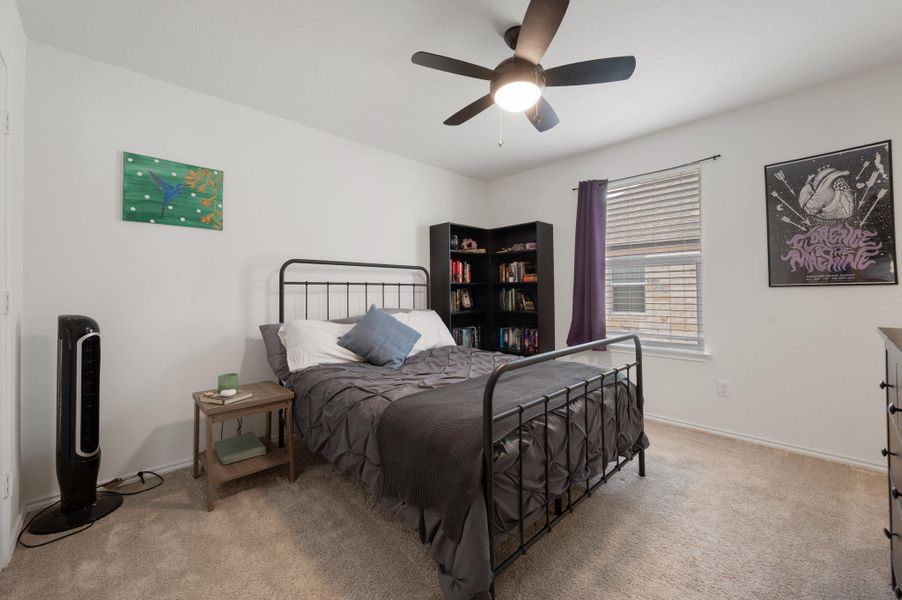 Bedroom with a ceiling fan and light colored carpet