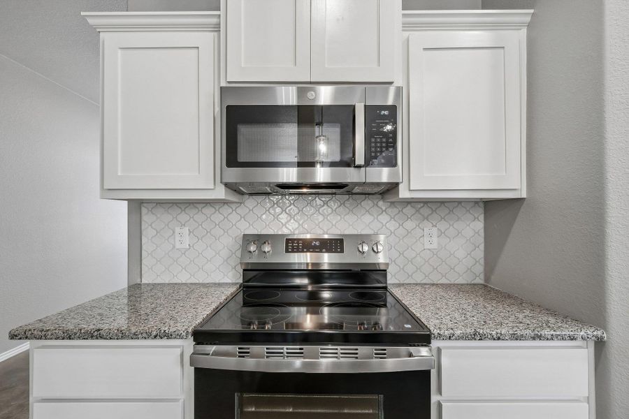 Well-appointed kitchen featuring a modern electric range, sleek microwave, and durable granite countertops. Well-appointed kitchen featuring a modern electric range, sleek microwave, and durable granite countertops.