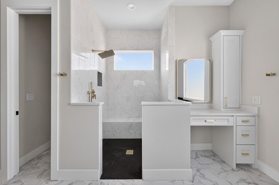 A modern walk-in shower anchors this space alongside a built-in vanity station.