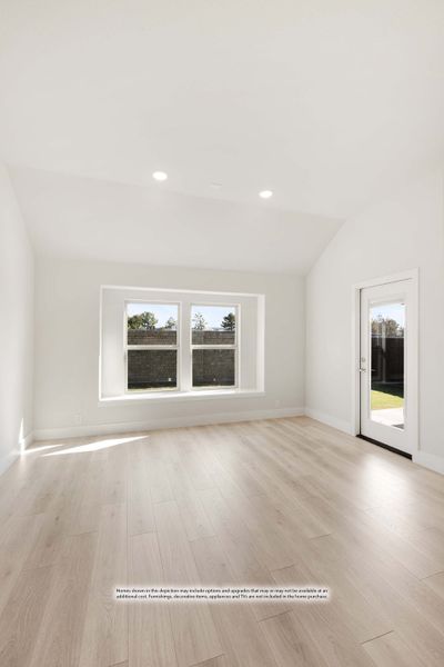 Empty room with vaulted ceiling, light wood floors, double window, and glass door to backyard. Empty room with vaulted ceiling, light wood floors, double window, and glass door to backyard.