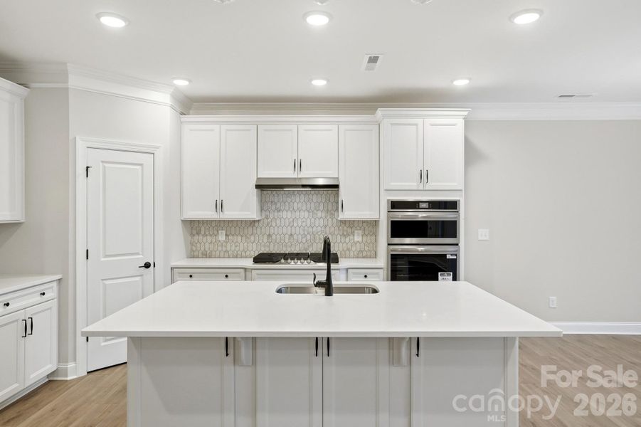 Kitchen features white cabinets, black hardware and quartz countertops