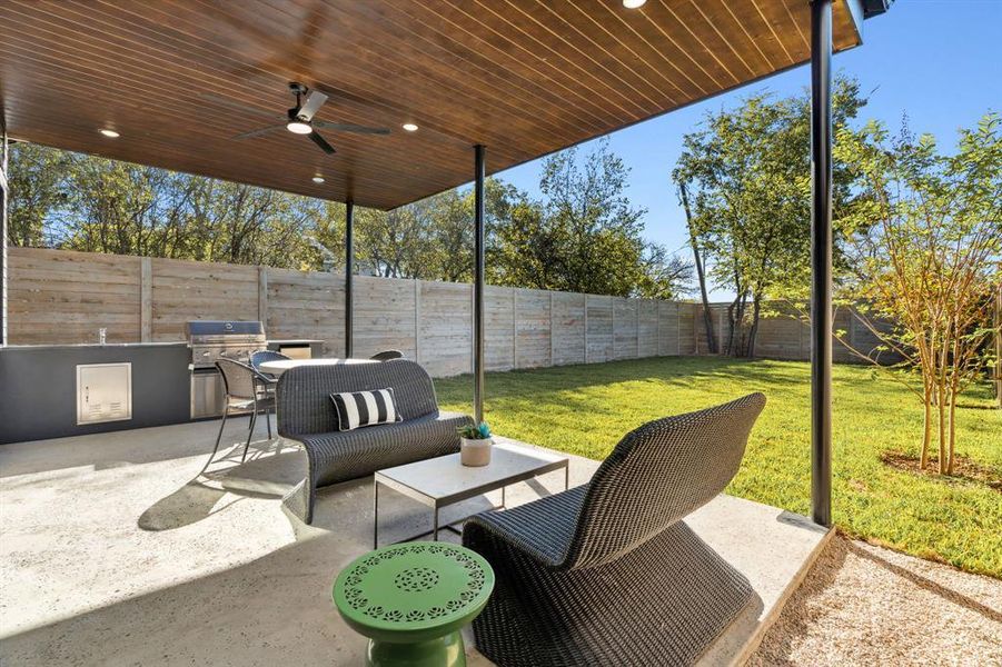 Fenced backyard featuring a patio, an outdoor kitchen, and a ceiling fan