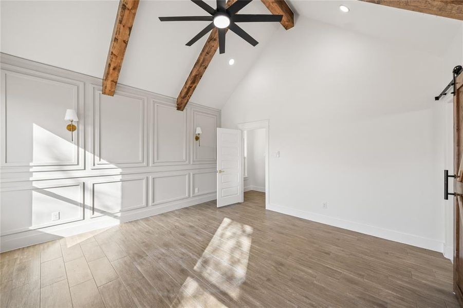 Unfurnished living room featuring a barn door, a decorative wall, light wood-style floors, ceiling fan, and recessed lighting