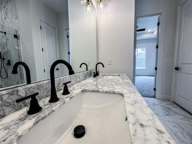 Full bathroom featuring a marble finish shower, double vanity, and marble finish floors Full bathroom featuring a marble finish shower, double vanity, and marble finish floors