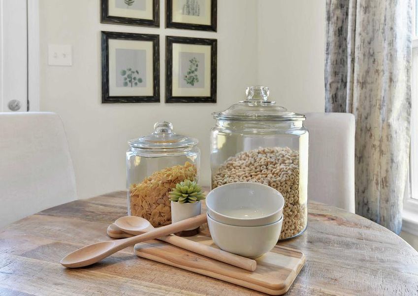 Walnut staged home with two large glass cereal jars, wooden spoon and cutting board, and white bowls on the kitchen table Walnut staged home with two large glass cereal jars, wooden spoon and cutting board, and white bowls on the kitchen table