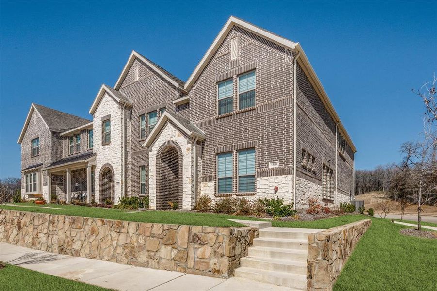 View of front of property featuring stone siding, brick siding, and a front yard