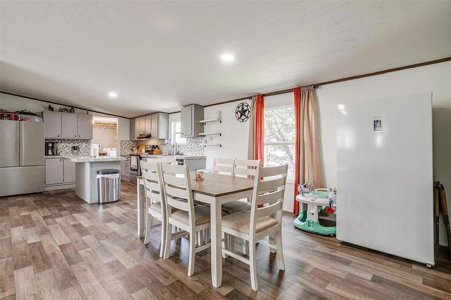 Dining space with vaulted ceiling, sink, and light hardwood / wood-style flooring